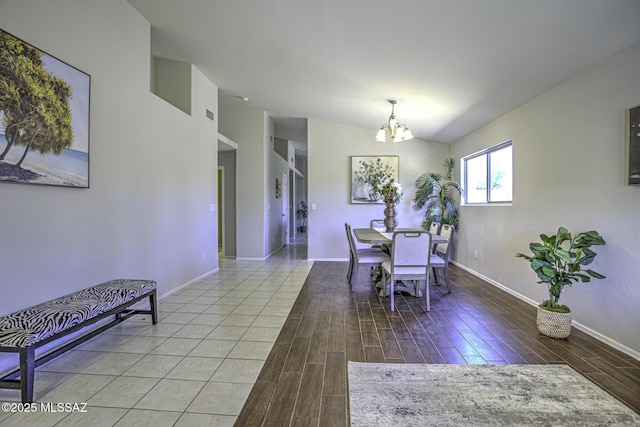 dining room with wood finished floors, an inviting chandelier, baseboards, and lofted ceiling