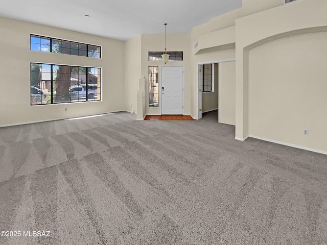 unfurnished living room featuring carpet floors and a high ceiling