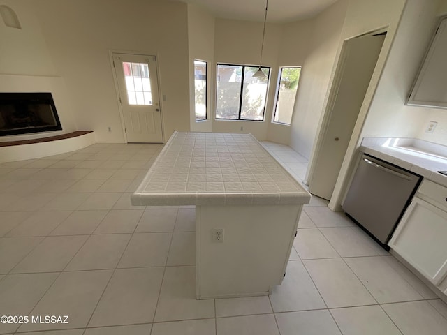 kitchen with tile countertops, light tile patterned floors, a kitchen island, and white cabinets