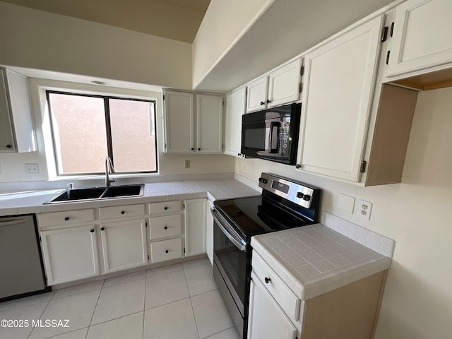 kitchen with sink, tile counters, stainless steel appliances, and white cabinets