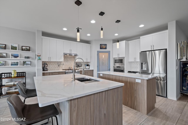 kitchen featuring an island with sink, appliances with stainless steel finishes, and white cabinets