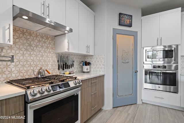 kitchen with stainless steel appliances, white cabinets, light countertops, and under cabinet range hood