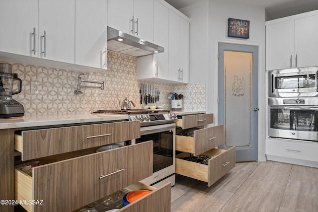 kitchen with light countertops, appliances with stainless steel finishes, white cabinets, and under cabinet range hood