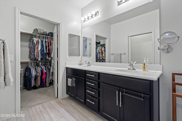 full bathroom featuring double vanity, a spacious closet, and a sink