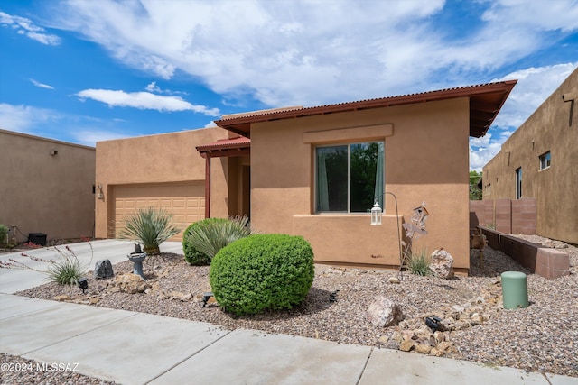 view of front of property with a garage, driveway, fence, and stucco siding