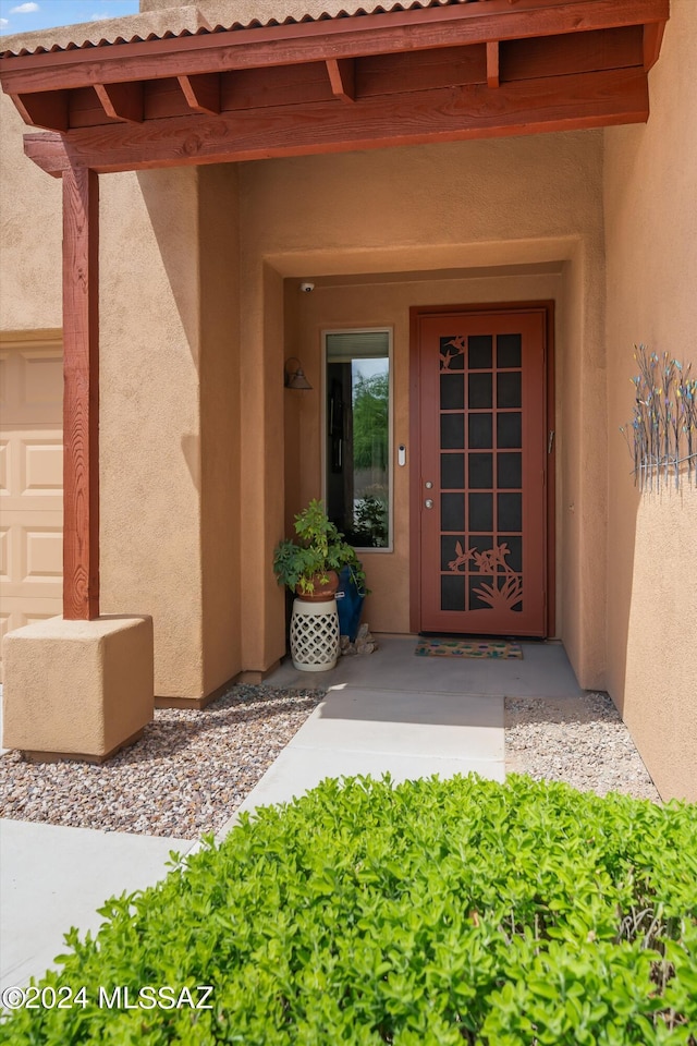 doorway to property featuring an attached garage and stucco siding