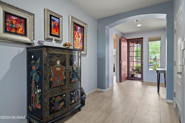 entrance foyer featuring arched walkways, light tile patterned floors, visible vents, and baseboards