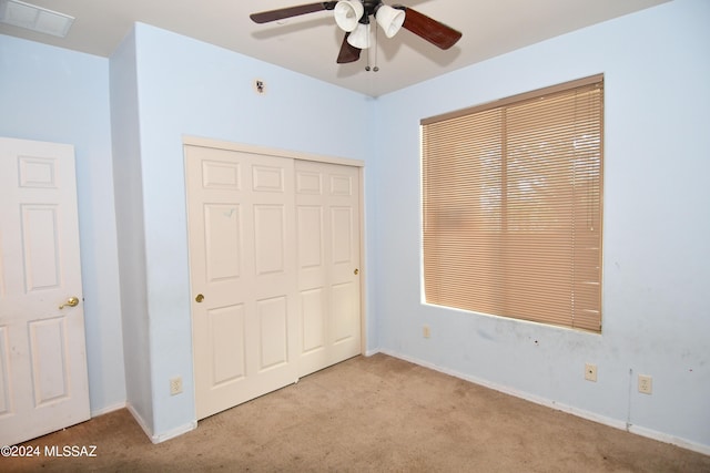 unfurnished bedroom featuring a closet, light colored carpet, and ceiling fan