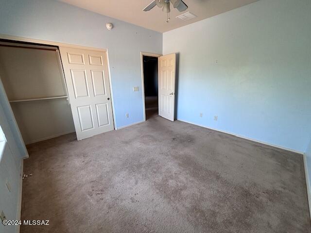 unfurnished bedroom with a closet, ceiling fan, and carpet flooring