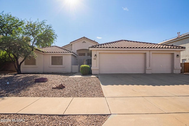 mediterranean / spanish-style house featuring a tiled roof, driveway, stucco siding, and an attached garage
