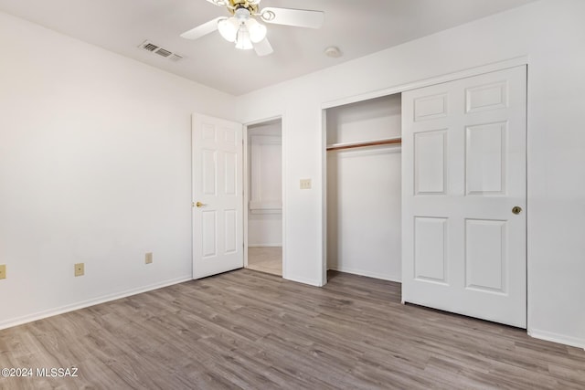 unfurnished bedroom featuring baseboards, visible vents, a closet, and wood finished floors