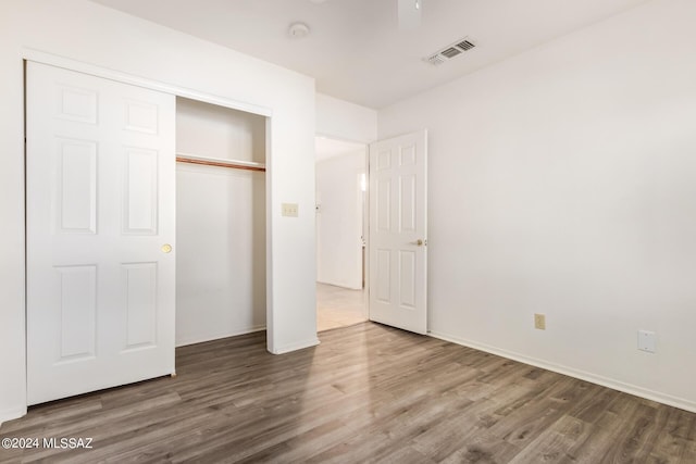 unfurnished bedroom featuring baseboards, visible vents, a closet, and wood finished floors