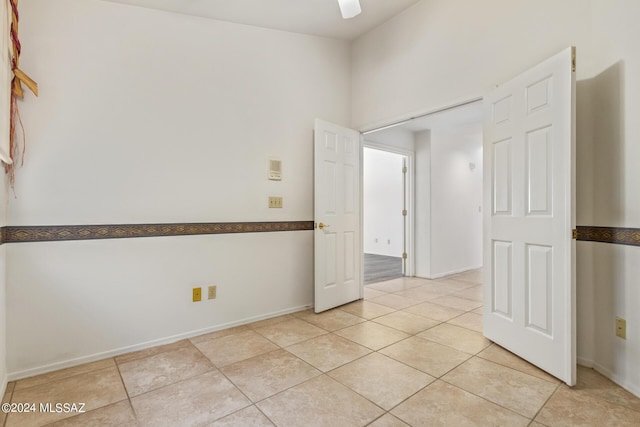 unfurnished room featuring a ceiling fan, light tile patterned floors, and baseboards