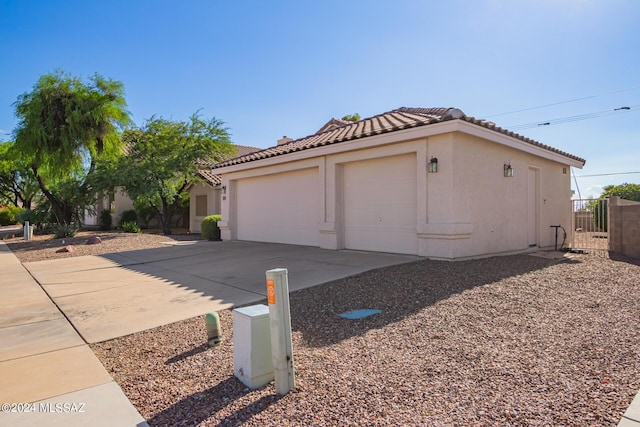 exterior space featuring a tile roof, driveway, stucco siding, an attached garage, and fence