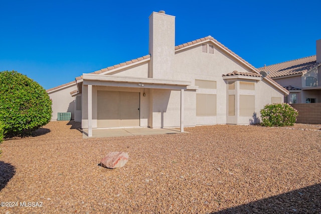 back of property with fence, a patio, a chimney, a tile roof, and stucco siding