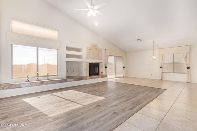 unfurnished living room featuring light tile patterned flooring, high vaulted ceiling, a tile fireplace, a ceiling fan, and visible vents