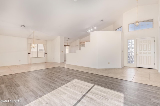 entrance foyer with rail lighting, an inviting chandelier, high vaulted ceiling, visible vents, and wood finished floors