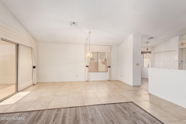 spare room with a notable chandelier, lofted ceiling, visible vents, and tile patterned flooring