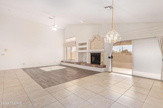 unfurnished living room featuring visible vents, tile patterned floors, ceiling fan with notable chandelier, and a tile fireplace