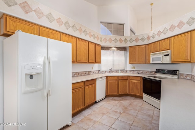 kitchen featuring white appliances, light countertops, a sink, and brown cabinetry