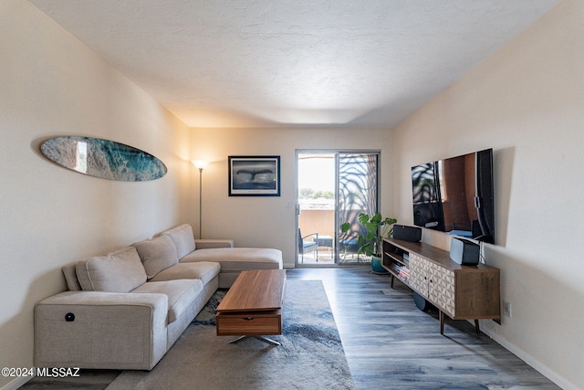 living room with a textured ceiling, baseboards, and wood finished floors