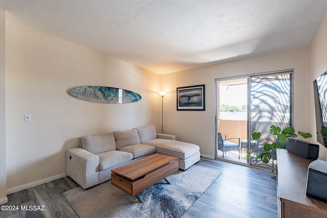 living area featuring a textured ceiling, baseboards, and wood finished floors