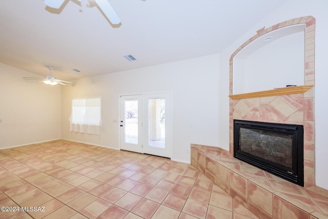 unfurnished living room featuring ceiling fan, visible vents, a tiled fireplace, baseboards, and light tile patterned flooring