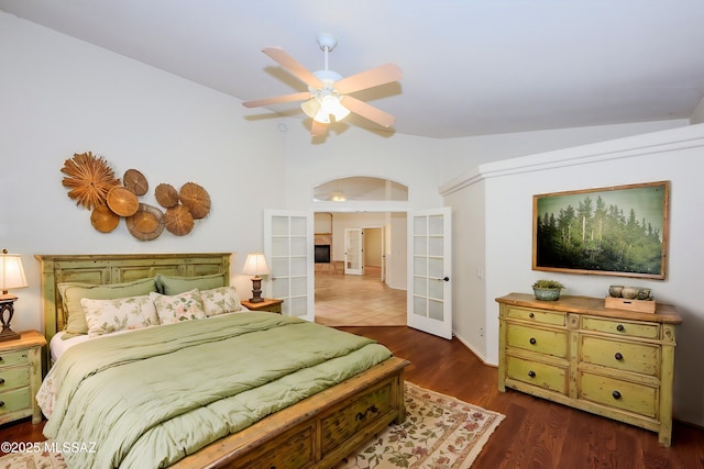 bedroom with arched walkways, french doors, baseboards, wood finished floors, and lofted ceiling