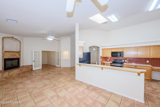 kitchen with a fireplace, a peninsula, tasteful backsplash, visible vents, and black appliances