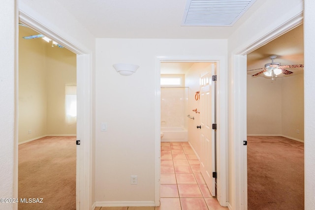 corridor with light tile patterned floors, baseboards, light colored carpet, and visible vents