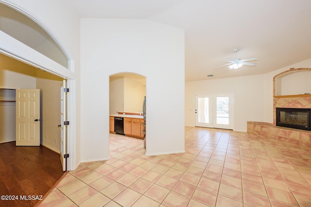 unfurnished living room with light tile patterned flooring, ceiling fan, vaulted ceiling, and a tile fireplace
