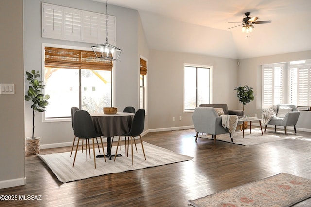 dining area featuring dark wood-type flooring, lofted ceiling, and ceiling fan with notable chandelier