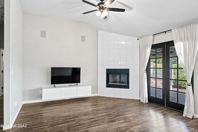 unfurnished living room featuring a tile fireplace, french doors, dark hardwood / wood-style floors, and ceiling fan