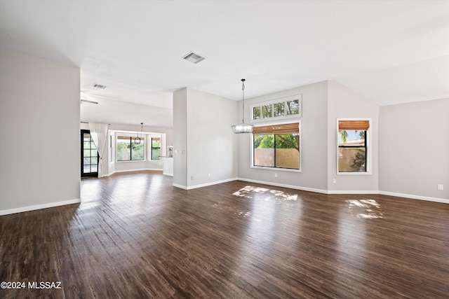 unfurnished living room with lofted ceiling, a chandelier, and dark hardwood / wood-style floors