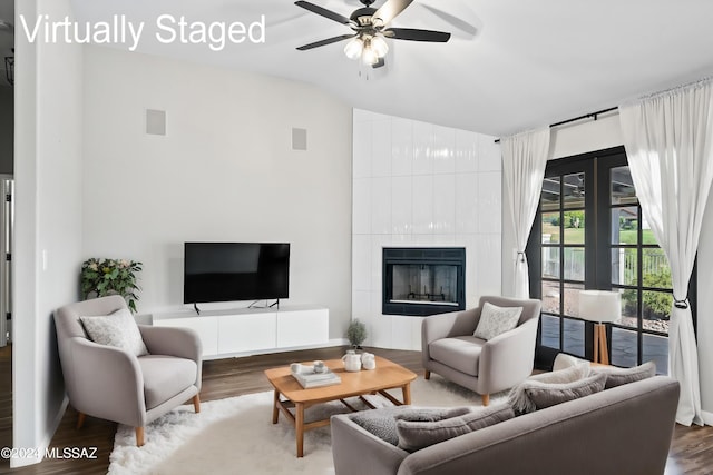 living room with a tiled fireplace, ceiling fan, and wood-type flooring