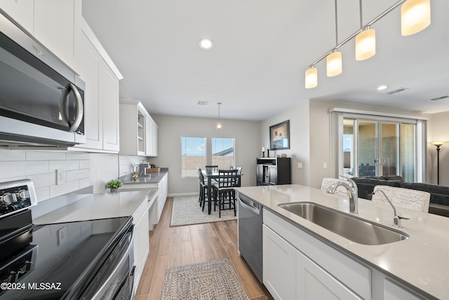 kitchen with sink, decorative backsplash, light hardwood / wood-style floors, white cabinetry, and stainless steel appliances