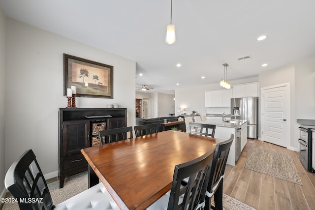 dining room featuring ceiling fan, sink, and light hardwood / wood-style flooring