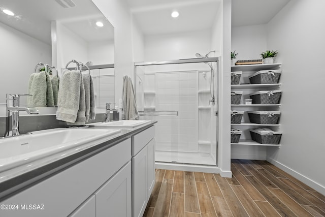 bathroom featuring wood-type flooring, a shower with door, and vanity