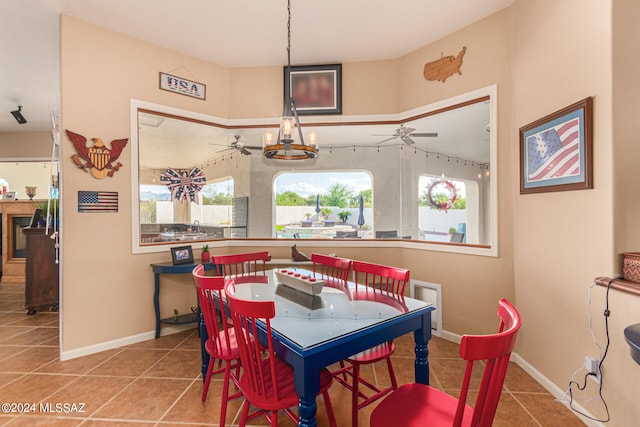 tiled dining space featuring ceiling fan with notable chandelier