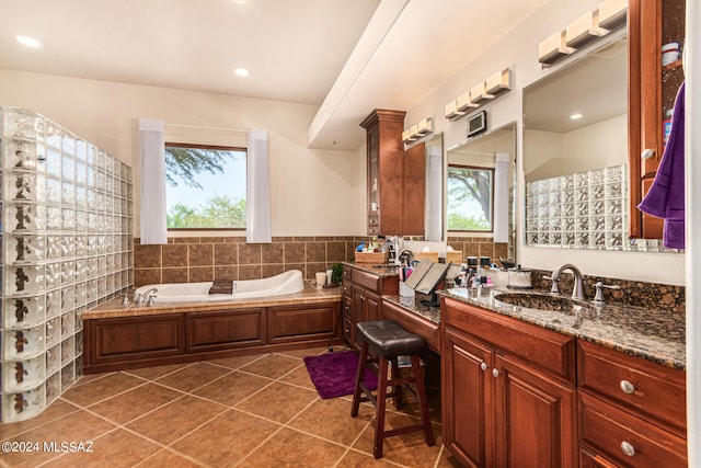 bathroom with vanity, a bath, a healthy amount of sunlight, and tile patterned flooring