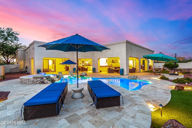 pool at dusk with a patio area and an outdoor hangout area