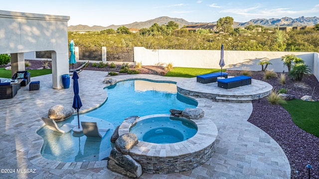 view of pool featuring a patio area, a mountain view, and an in ground hot tub