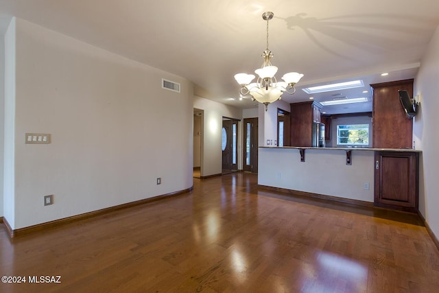 interior space with a chandelier, baseboards, visible vents, and wood finished floors