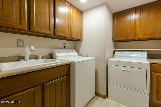 laundry area with cabinet space, light tile patterned floors, independent washer and dryer, and a sink