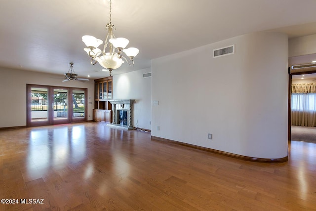 unfurnished living room featuring visible vents, a fireplace with raised hearth, baseboards, and wood finished floors