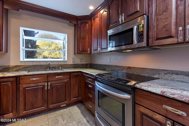 kitchen with a sink, stainless steel appliances, and light stone counters