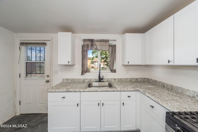 kitchen featuring sink, stove, light stone countertops, and white cabinets