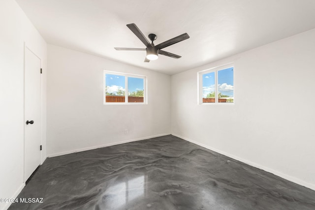 spare room with ceiling fan, concrete flooring, and a healthy amount of sunlight