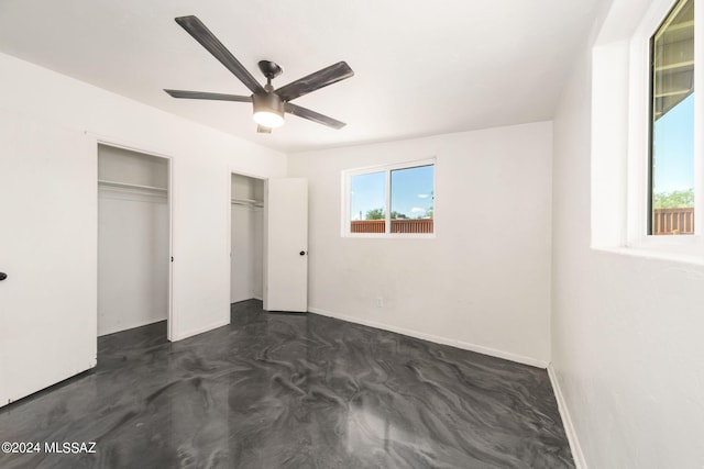 unfurnished bedroom featuring ceiling fan and two closets