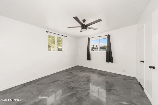 spare room featuring ceiling fan, concrete flooring, and a healthy amount of sunlight
